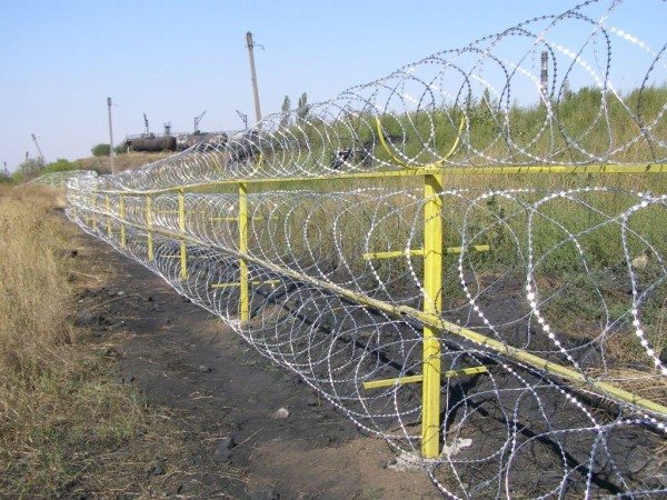 Забор с колючей проволокой даже не требует особых капитальных вспомогательных  приспособлений, по крайней мере, дизайнерская сторона вопроса отходит на второй план